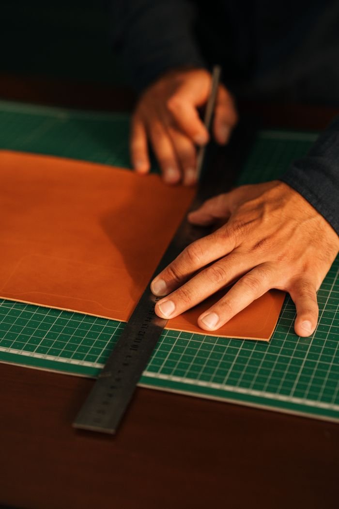 about-02 Hands carefully cutting leather on a cutting mat, showcasing craftsmanship and precision.
